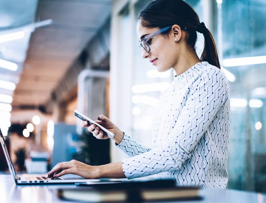 Businesswoman using phone and laptop